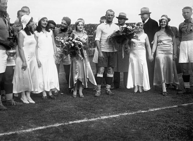 Just before the beginning of the semi-final between Uruguay and Yugoslavia, five pupils of the “Instituto Nacional de Señoritas” (Young Ladies’ Finishing School) wearing dresses bearing the colours of the national flag- a golden one, two white ones and two blue ones- give bouquets to the captains of the respective teams, José Nasazzi and Milutin Yokovitch. Centenario Stadium. July 27th, 1930.