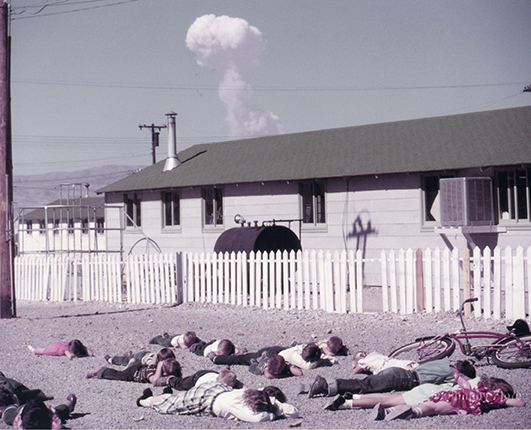 Operation name: Tumbler-Snapper.
Test name: Charlie.
Date and time: April 22, 1952, 09:30.
Test location: Range in Nevada.
Explosion type, explosive placement: aerial, airdrop.
Explosion height: 1050 m.
Yield: 31 kilotons.
Rural schoolchildren practicing the duck and cover protection method with a real atomic bomb explosion in the background. (Duck and Cover was American educational and propaganda film about civil defence, filmed in 1952 by the US Government).
The photo was taken in Indian Springs, Nevada, located 40 km from the epicentre.
Photo: John Flory.
Source: Frank Zodl/ThePhotoArchive.