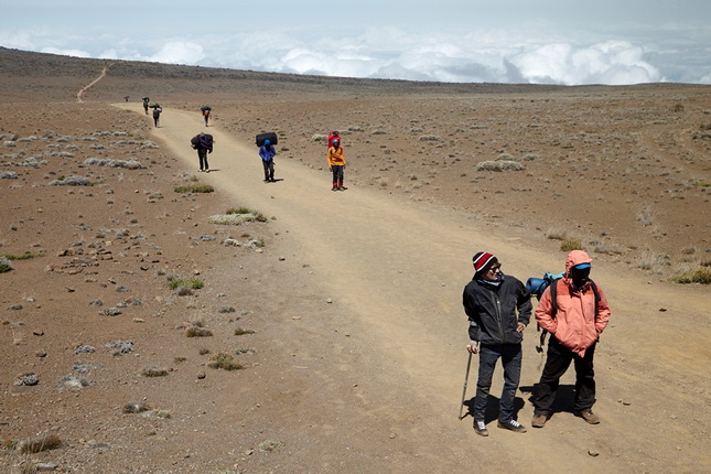 Стив Ремих.
Саша Шульчев и его гид идут сквозь горную пустыню по дороге в третий, и последний, лагерь – Кибо Хатт. Маршрут на вершину Килиманджаро пролегает через тропический лес, болото, горные пустыни и ледники.
Июнь, 2014