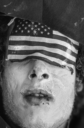 Jean-Pierre Laffont.
30th Rep Convention Miami 72 Man with eyes covered with US Flag.
Miami, FL - August 23, 1972
President Richard Nixon's reelection campaign demonstrators wear costumes and make-up to act out scenes of death and misery.
© Jean-Pierre Laffont / from the book “Photographer's Paradise. Turbulent America 1960-1990” (Glitterati)